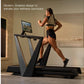 Woman running on black and gray modern treadmill with tablet display in minimalist room setting
