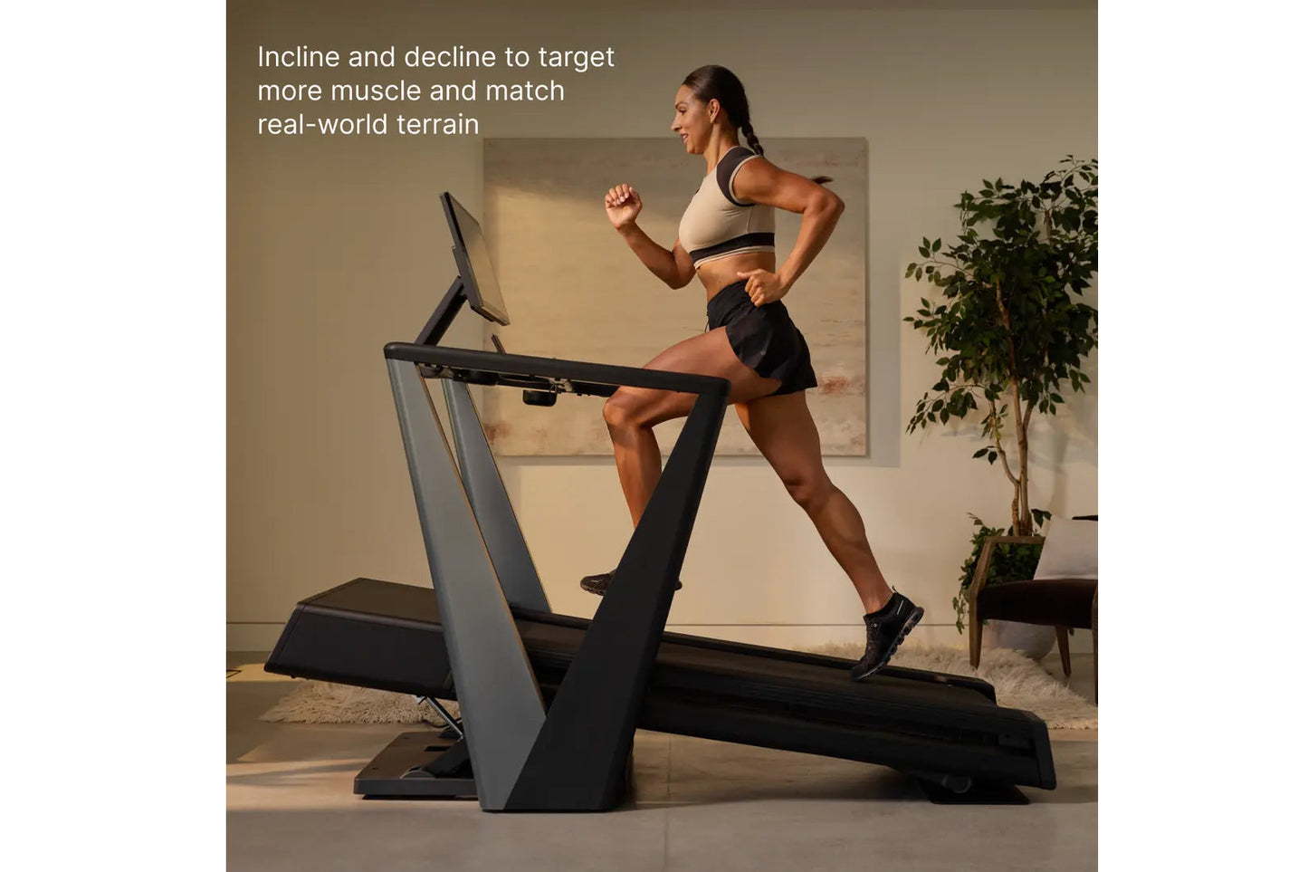 Woman running on incline treadmill wearing cream sports bra and black shorts, demonstrating adjustable incline feature in hom