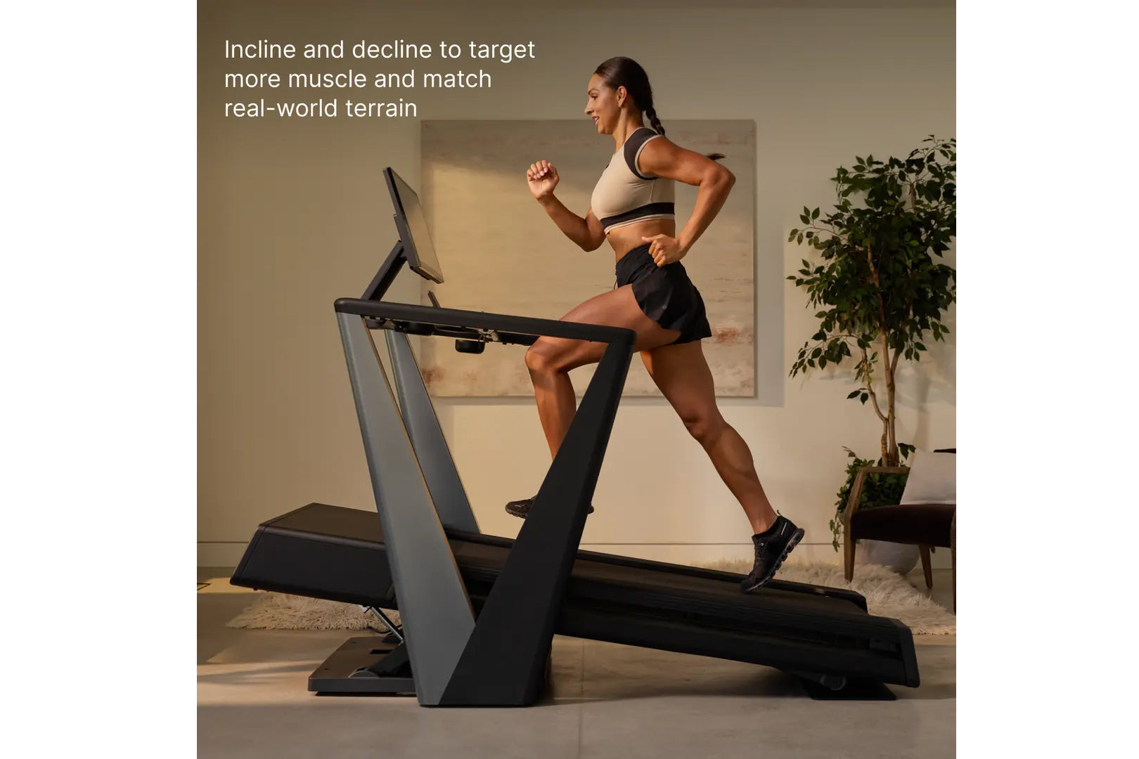 Woman running on incline treadmill wearing cream sports bra and black shorts, demonstrating adjustable incline feature in hom