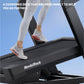 Runner wearing white sneakers with orange accents on NordicTrack treadmill with cushioned black deck