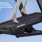 Runner in white sneakers and white leggings on black NordicTrack treadmill with cushioned deck against blue sky background