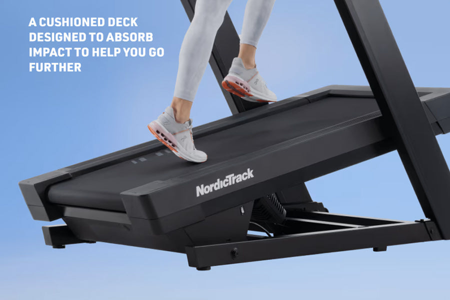 Runner in white sneakers and white leggings on black NordicTrack treadmill with cushioned deck against blue sky background