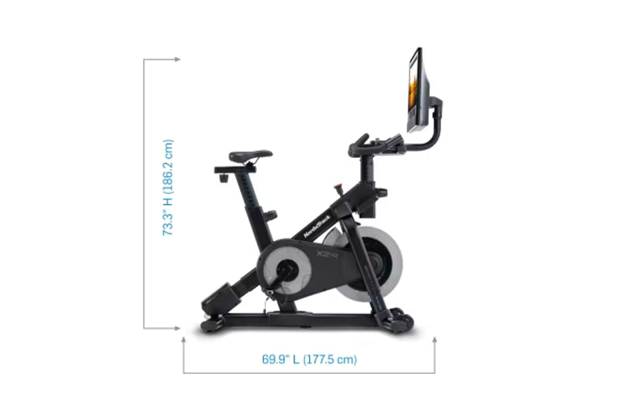 Black upright stationary exercise bike with gray flywheel and digital display console mounted on handlebar, shown with dimens