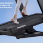 Person running on black NordicTrack treadmill with cushioned deck, wearing white sneakers with orange accents and white leggi
