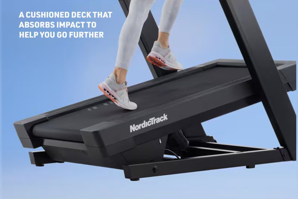 Person running on black NordicTrack treadmill with cushioned deck, wearing white sneakers with orange accents and white leggi