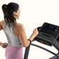 Woman in gray tank top and pink leggings running on black ProForm treadmill with digital display, shown from side profile