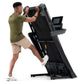 Man using black NordicTrack T-Series 10 treadmill with digital display, wearing olive green shirt and beige shorts
