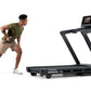 Man in olive green shirt and tan shorts performing interval training on NordicTrack black treadmill with digital display