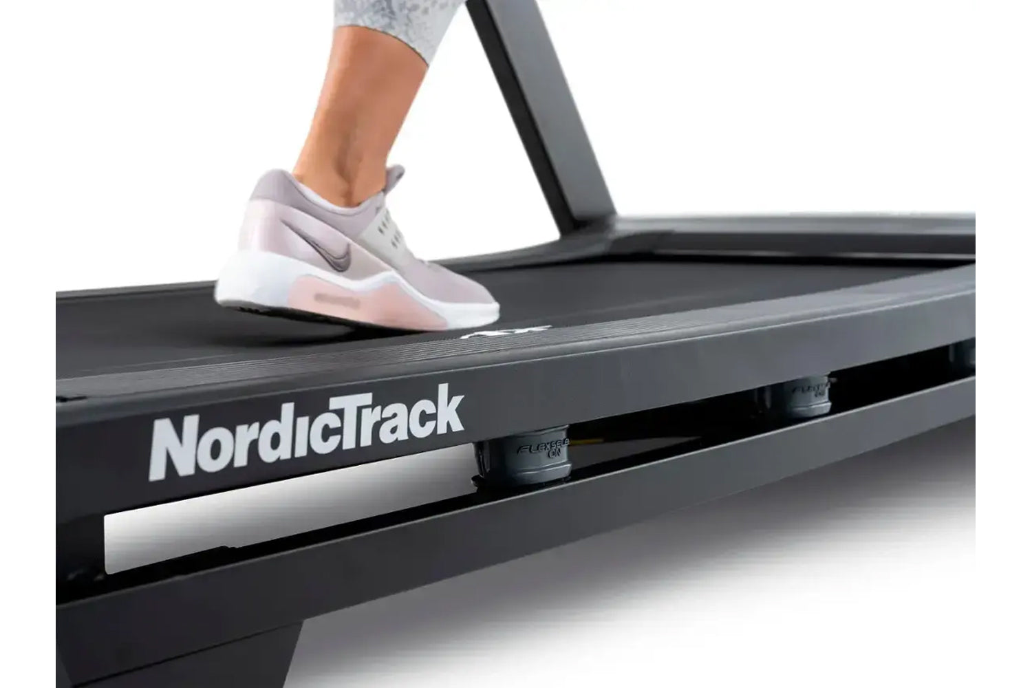 Person wearing white and pink sneaker running on NordicTrack black treadmill with handrail