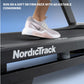 White and gray running shoe with cushioned sole worn by model on NordicTrack treadmill deck