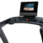 Black treadmill console with integrated tablet mount displaying workout video, control buttons including start and stop, on w