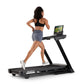 Black NordicTrack treadmill with tablet holder, worn by model in black sports bra and gray shorts, on white background