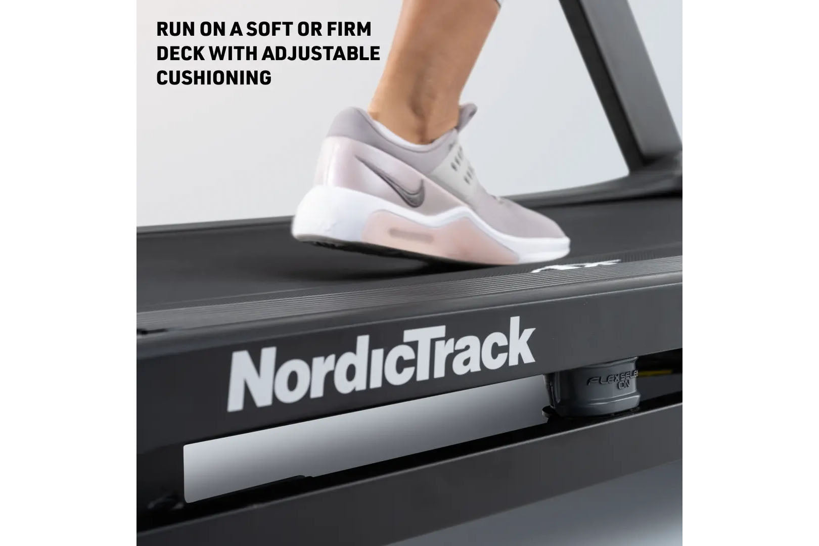 White and gray running shoe with cushioning worn by runner on NordicTrack treadmill deck