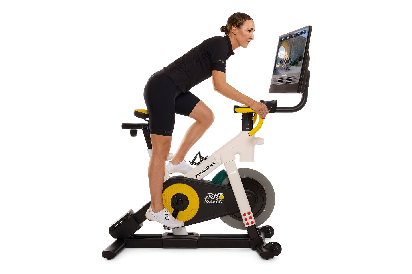 Woman in black athletic wear riding NordicTrack stationary bike with yellow wheel and display screen, white background
