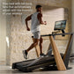Man running on NordicTrack treadmill with wood and black frame in modern loft space with brick wall