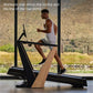 Man in white tank top running on black and wood NordicTrack treadmill with incline feature, facing large windows overlooking 
