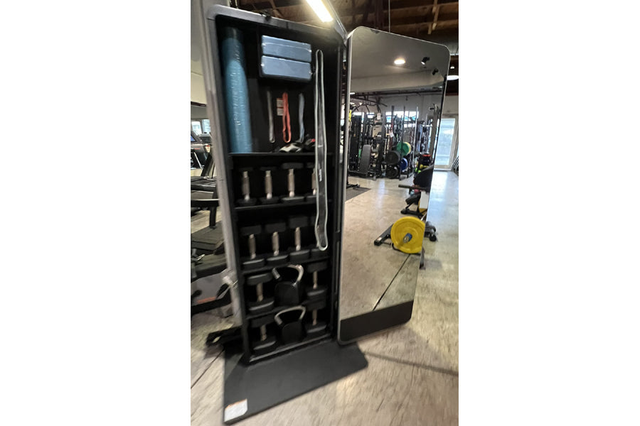 Black mirrored home gym cabinet with open door displaying storage shelves, dumbbells, and resistance bands in gym setting