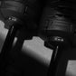 Pair of black NÜOBELL adjustable dumbbells marked 10 lb and 100 lb with textured grips, displayed on gray background