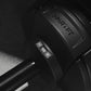 Black adjustable dumbbell marked "NÜOBELL" and "100+" shown in flat lay on textured surface