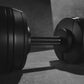 Black adjustable dumbbells with textured knurled handles and weight plates, displayed on concrete floor in black and white ph
