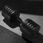 Pair of matte black adjustable dumbbells with metal handle and weight plates on gray surface