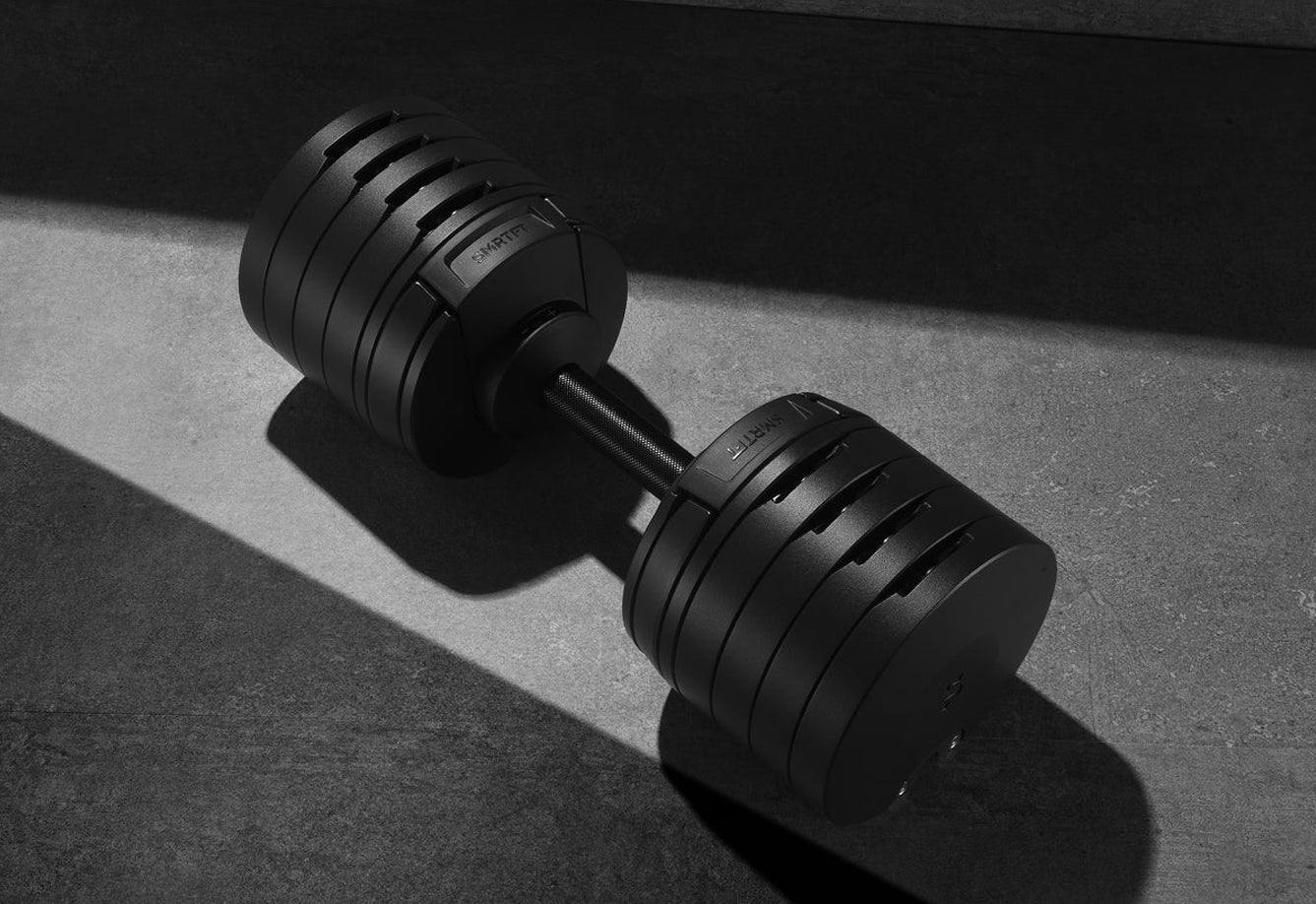 Pair of matte black adjustable dumbbells with metal handle and weight plates on gray surface