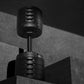 NÜOBELL adjustable dumbbell with matte black finish and metal stem, showing weight selector dial, displayed against concrete 
