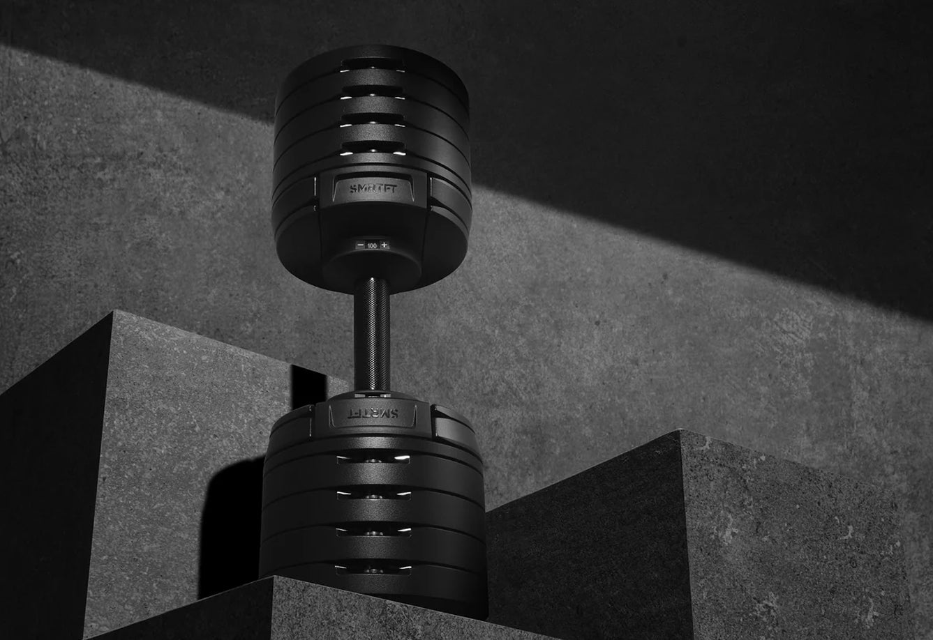 NÜOBELL adjustable dumbbell with matte black finish and metal stem, showing weight selector dial, displayed against concrete 