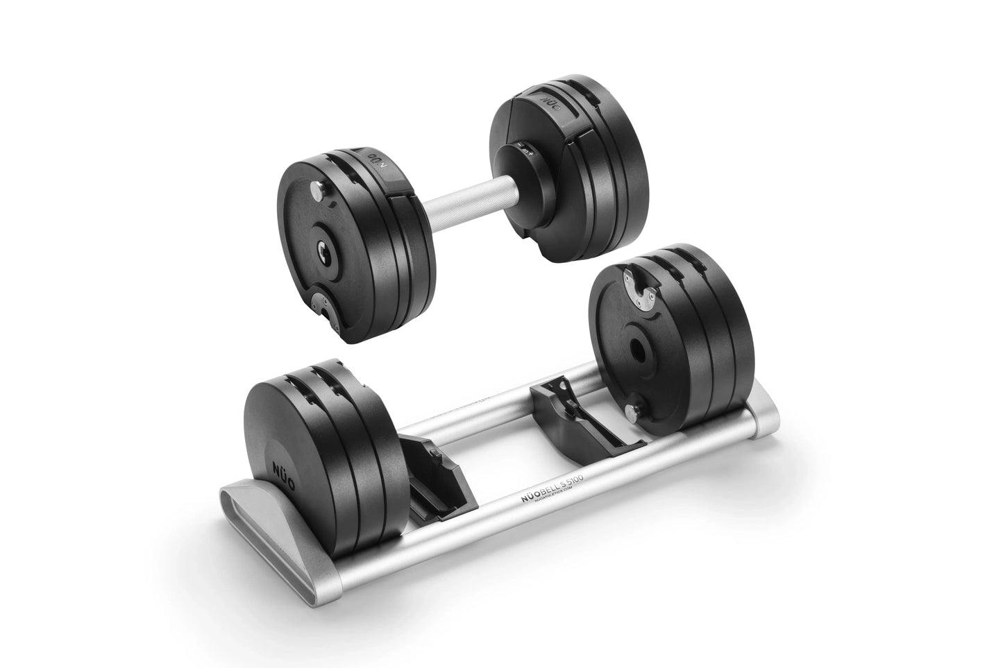 Pair of black adjustable dumbbells with silver handles, one standing alone and one resting on silver base tray, on white back