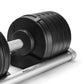Matte black adjustable dumbbell with white handle on silver weight plate stand, shown on white background