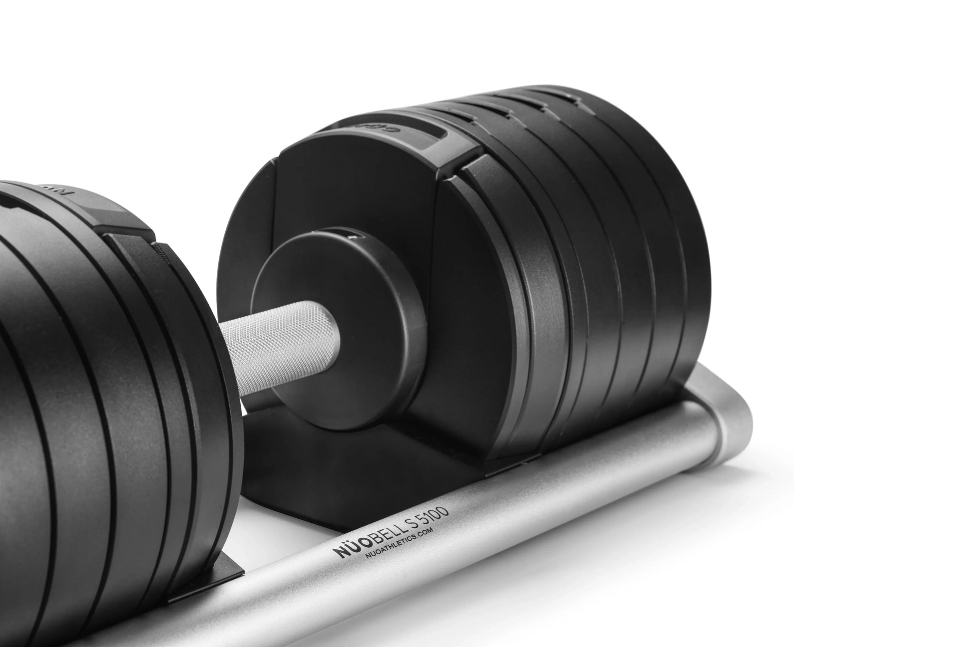 Matte black adjustable dumbbell with white handle on silver weight plate stand, shown on white background