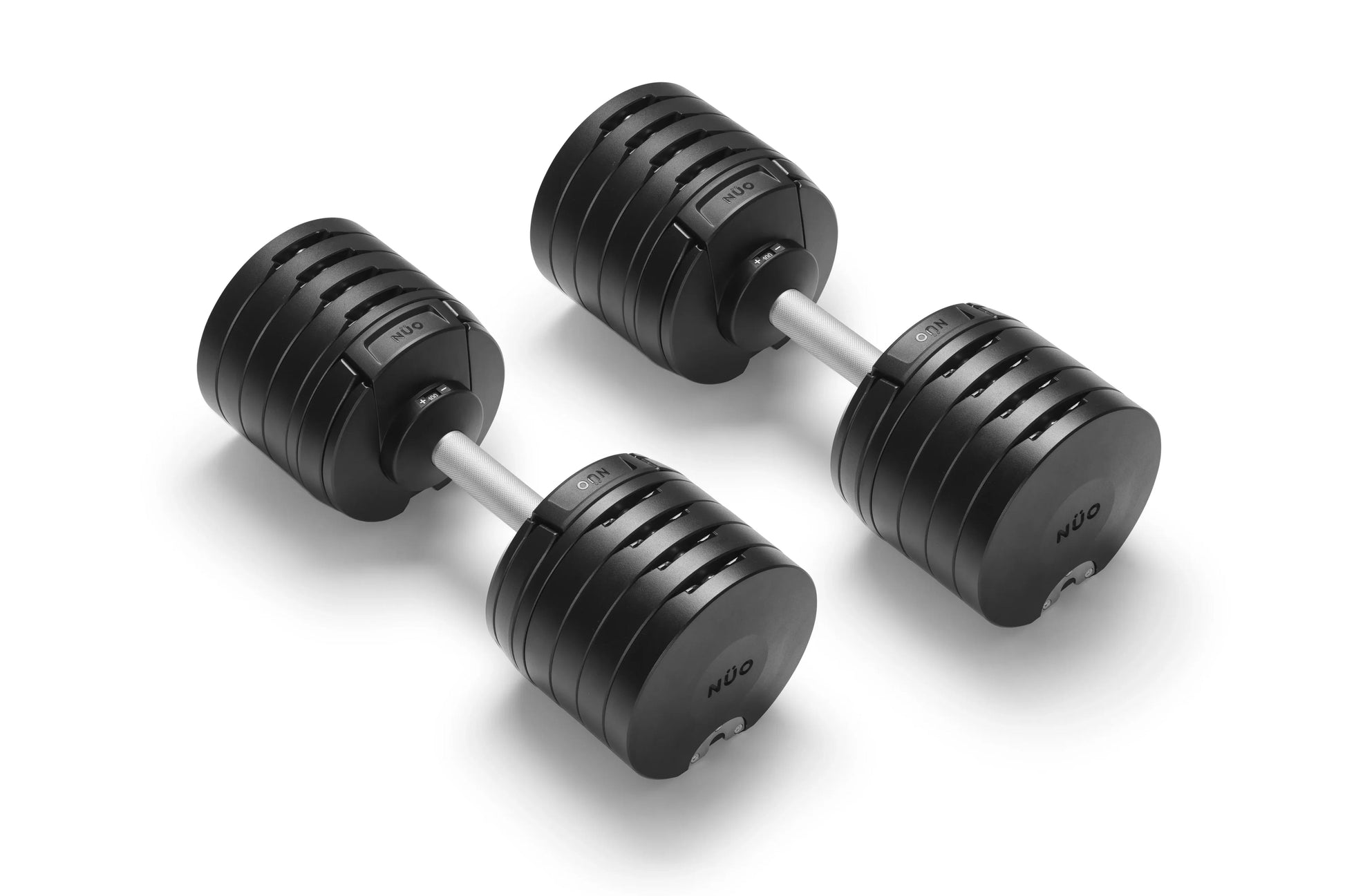 Pair of black adjustable dumbbells with grooved rubber grip plates and metal handles, shown on white background
