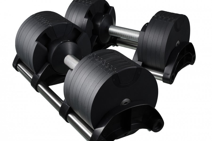 Pair of black adjustable dumbbells with textured grip, metal handles, and weight plates on stand, on white background