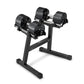 Pair of black adjustable dumbbells with textured rubber heads mounted on black metal stand, on white background