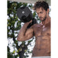 Shirtless man holding black adjustable dumbbell at shoulder height outdoors with trees in background