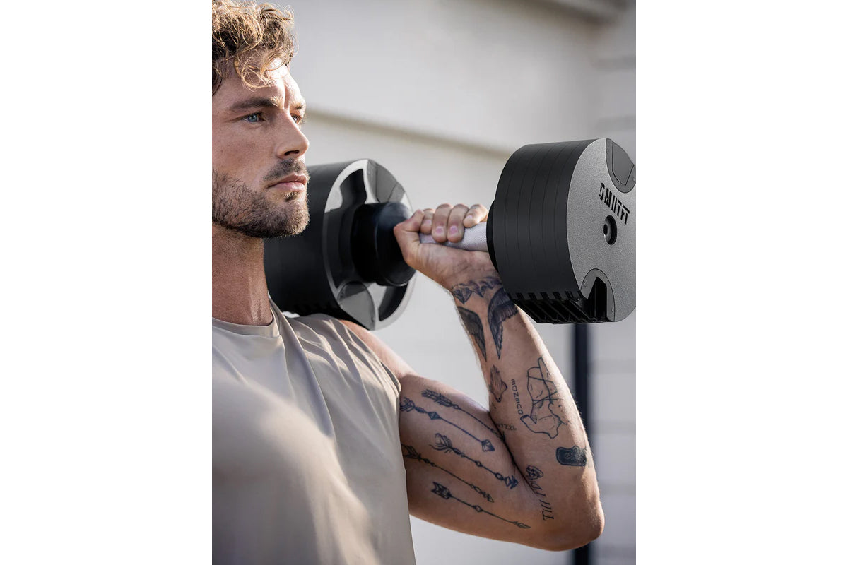 Man lifting black and gray adjustable dumbbell with weight dial, worn by model during exercise