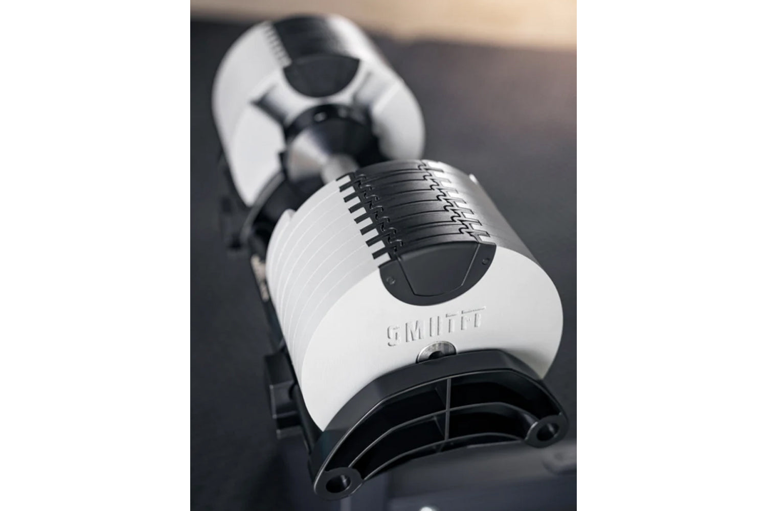 NÜOBELL 80lb adjustable dumbbell in white and black with metal weight plates and adjustment mechanism, shown on dark surface