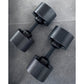 Three matte black adjustable dumbbells with ribbed weight plates and black handles on gray textured background