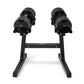 Pair of black adjustable dumbbells on matching stand, flat lay on white background