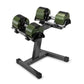 Pair of adjustable dumbbells with olive green and black weight plates on black stand, flat lay on white background