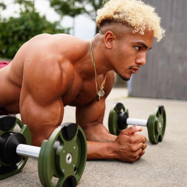 Man in plank position with green and black adjustable dumbbells during workout