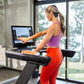 Woman wearing purple sports bra and red leggings using Octane OC220 treadmill with touchscreen display in bright home gym
