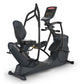 Black recumbent elliptical machine with digital display console, dual pedals, and padded seat on white background