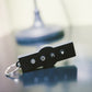 Black remote control with four illuminated buttons and metal key ring, displayed on blurred vibration machine background