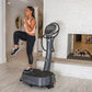 Woman using black Power Plate My7 vibration trainer in home gym, wearing pink sports bra and black leggings, reflected in mir
