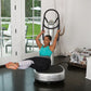 Woman in turquoise tank top and black leggings using Power Plate My5 vibration trainer with resistance band in home gym setti