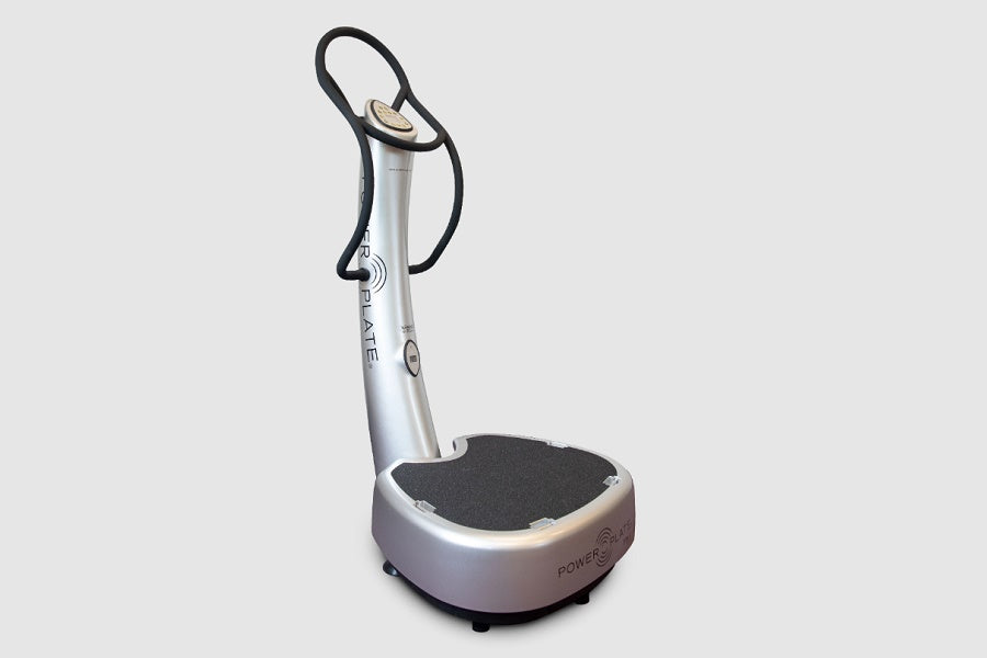 Silver and black vibration platform with curved handrails and textured footplate on white background