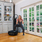 Woman exercising on black Power Plate My5 vibration trainer while holding pink dumbbells, wearing gray tank top and striped l