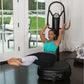 Woman in turquoise tank top and white leggings using black Power Plate My5 vibration trainer with resistance band in home gym