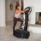 Woman wearing white tank top and burgundy leggings using black Power Plate My7 vibration trainer in fitness studio